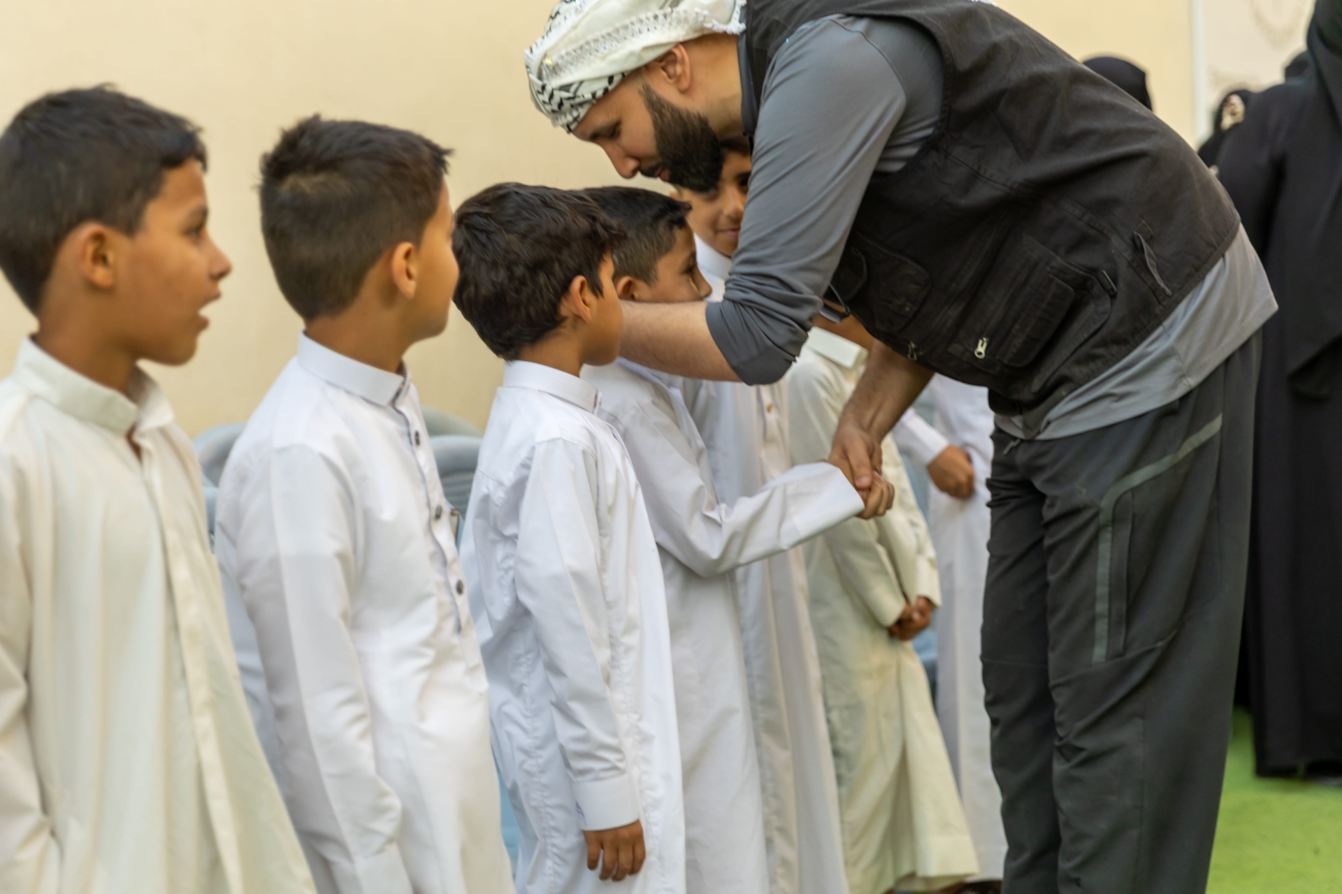 A visitor kneeling to greet a small child at the Suleiman Center, other children gathered nearby